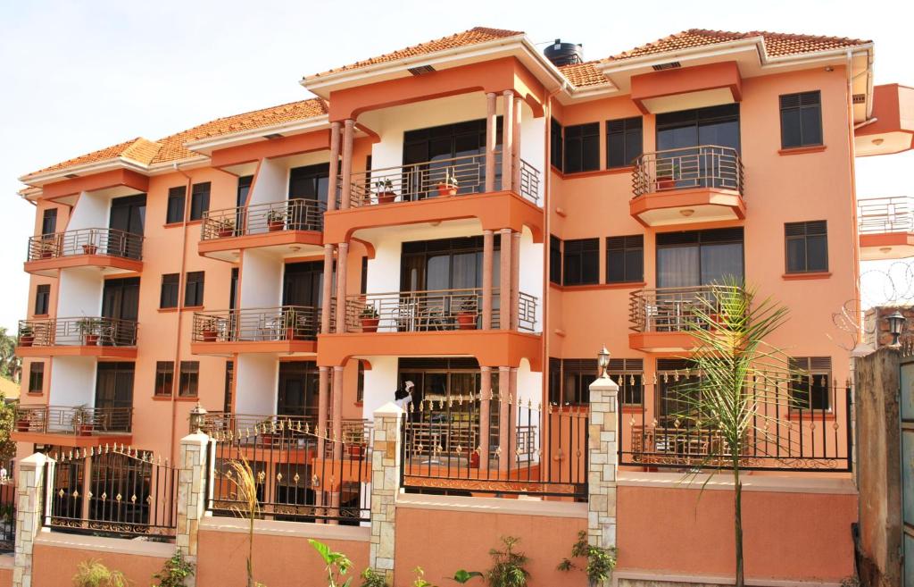 an orange building with balconies and a man sitting on a balcony at Tristar Hotel Kampala in Kampala