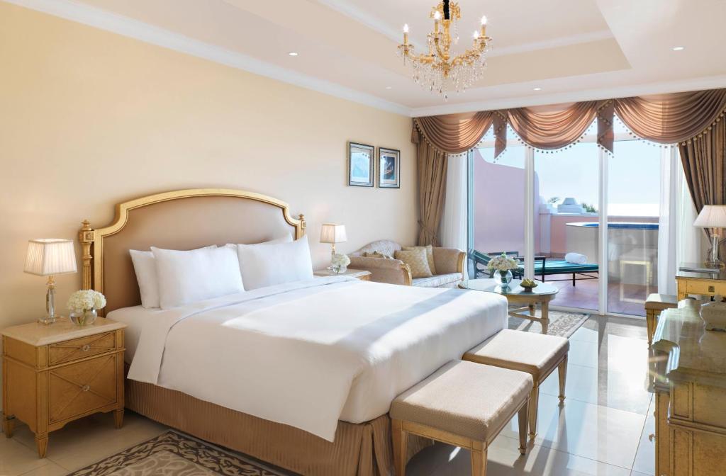 a bedroom with a large bed and a living room at Kempinski Hotel Palm Jumeirah in Dubai