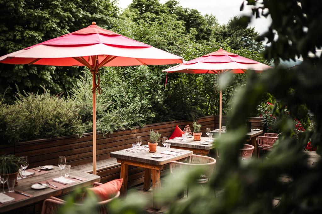 two tables with red umbrellas on a patio at Strasserwirt - Ansitz zu Tirol in Strassen