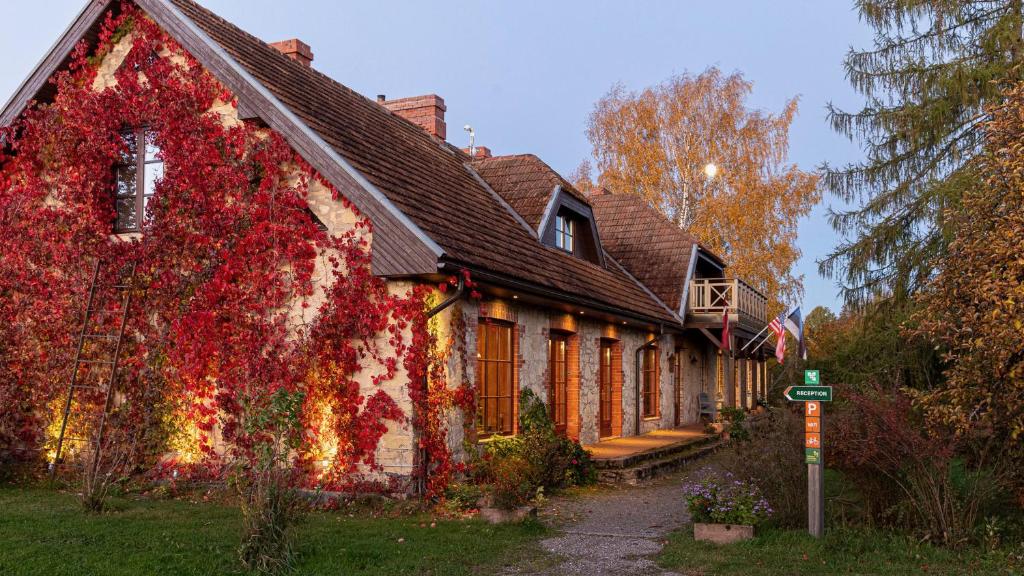 a house covered in red ivy in the yard at Karlamuiza Country Hotel in Kārļi