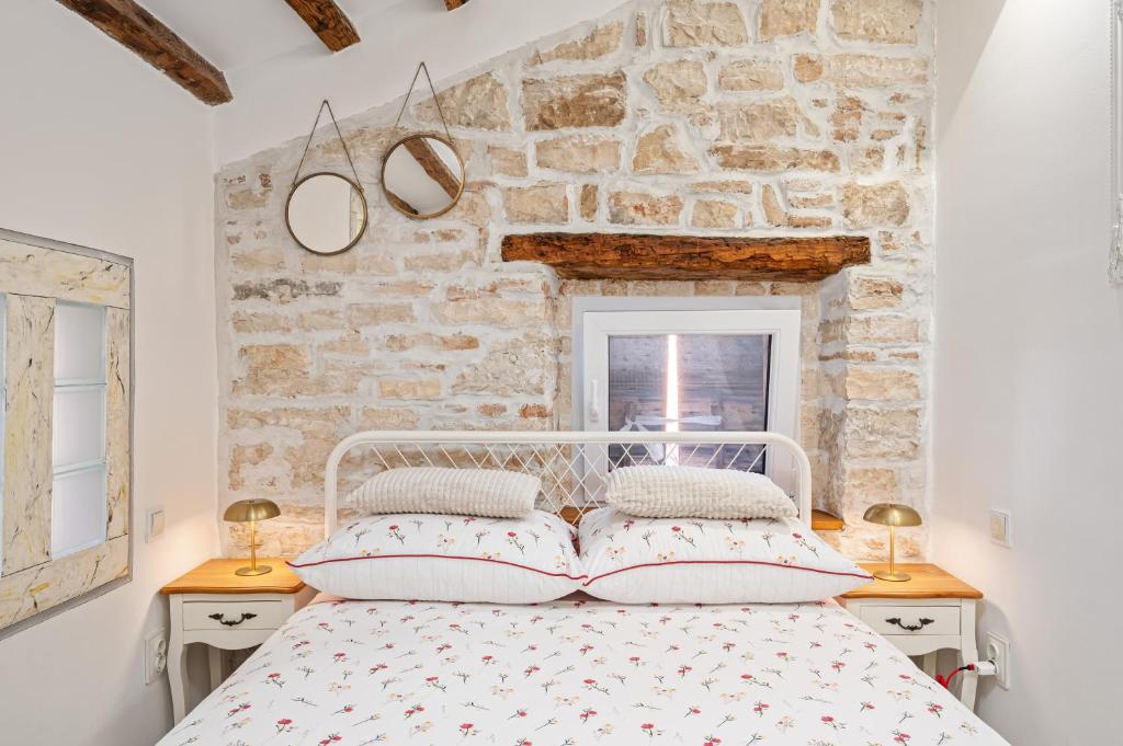 sypialnia z białym łóżkiem i kamienną ścianą w obiekcie Apartman tutto bene w Rovinj
