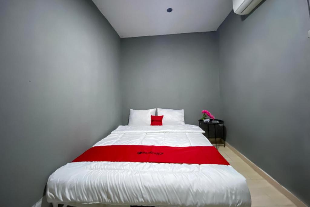 a bedroom with a white bed with a red blanket at RedDoorz at Marina City Waterfront in Pembunuh