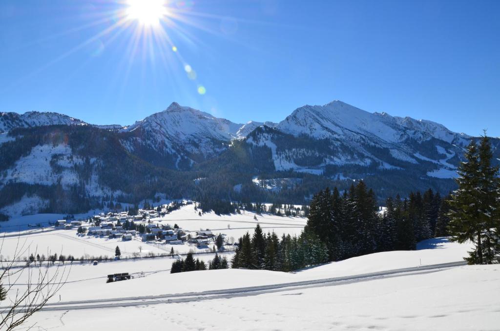 a snow covered mountain range with the sun in the sky at Haus Sennweg in Tannheim
