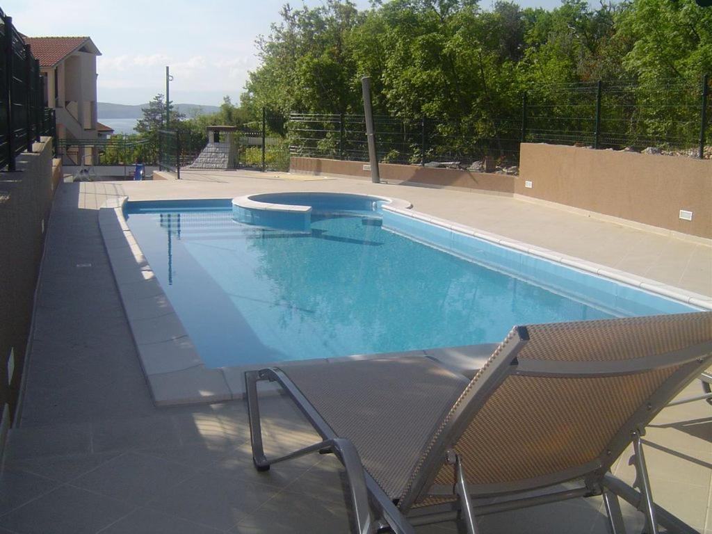 a large swimming pool with a chair at Apartmani Adriatica 2 in Dramalj