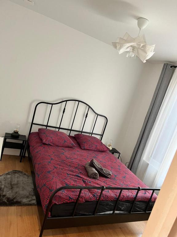 - un lit avec une couette et 2 oreillers rouges dans l'établissement Appartement de 27 m2 agréable et lumineux idéalement situé au coeur de la ville de Pierrefitte-sur-Seine, à Pierrefitte-sur-Seine