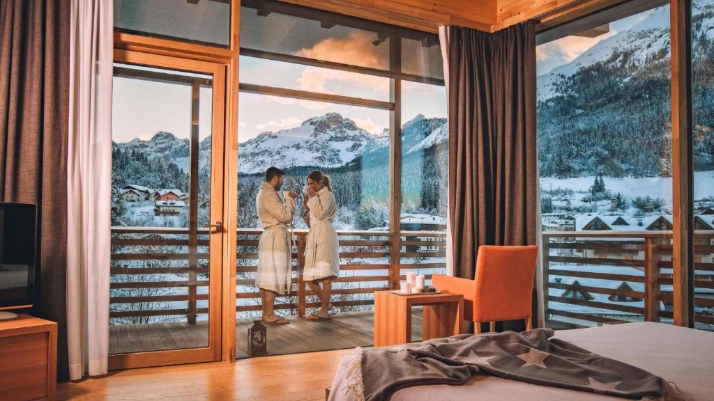 Dos mujeres de pie en un balcón en una habitación de hotel en Corona Dolomites Hotel, en Andalo