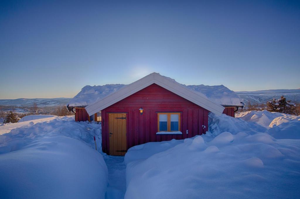 a red cabin with a bunch of snow around it at Charming Cabin with Old Timber, Fireplace & Views in Beitostøl