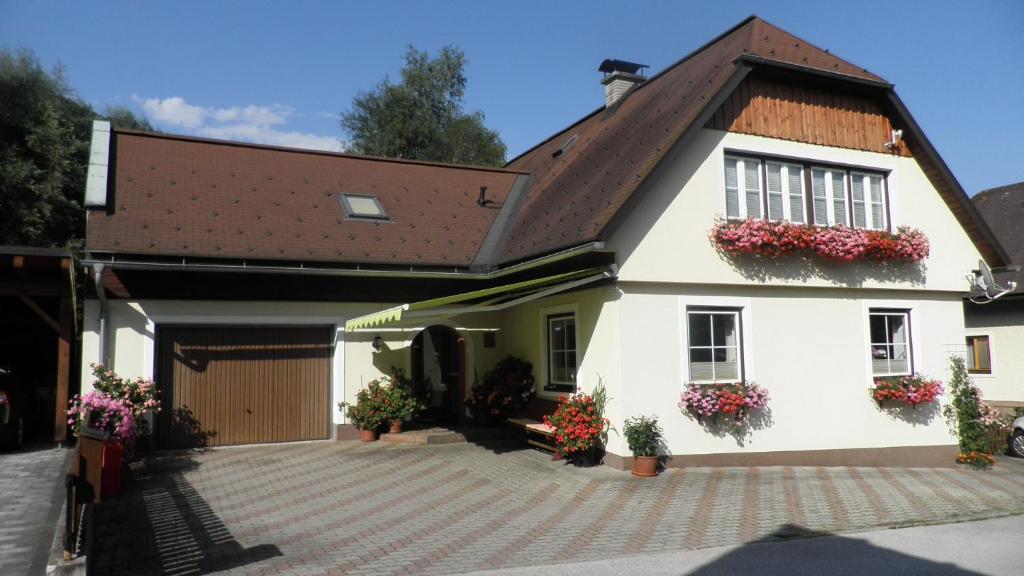 ein weißes Haus mit Blumen an den Fenstern in der Unterkunft Haus Anneliese in Pruggern