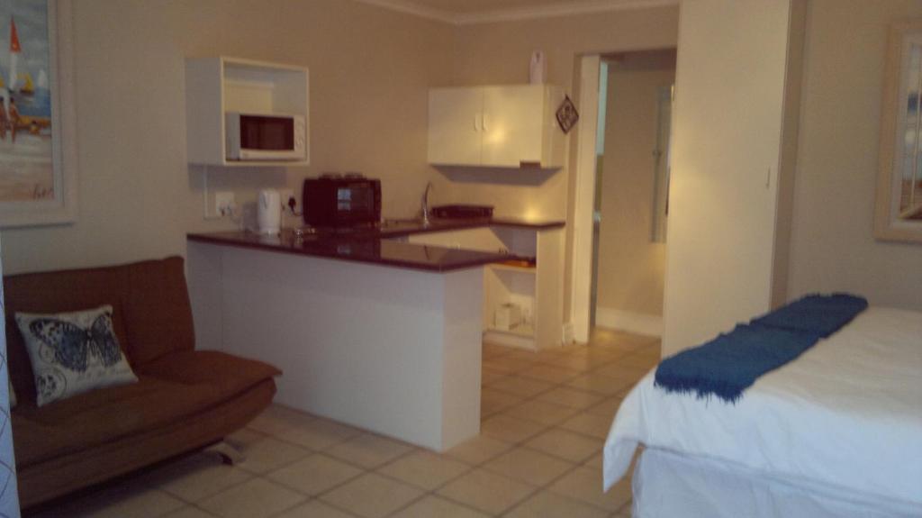 a room with a bed and a kitchen with a couch at 93 On Main Self Catering in Gonubie