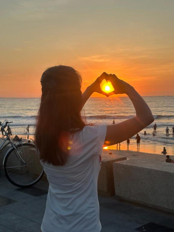 Una donna che si forma il cuore con le mani sulla spiaggia di Home Sun Moon - Home 1 a Phan Thiet