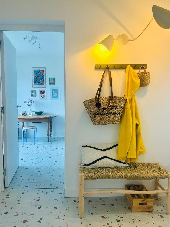 un couloir avec un banc avec un manteau jaune et une table dans l'établissement Gigi La Roza, à Perros-Guirec
