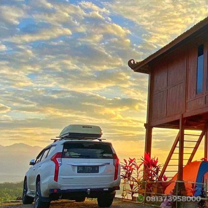 a car parked next to a building with a surfboard on the roof at Villa Murah BOEKIT 3G dgn View 3 Gunung & Sunrise in Cikidang
