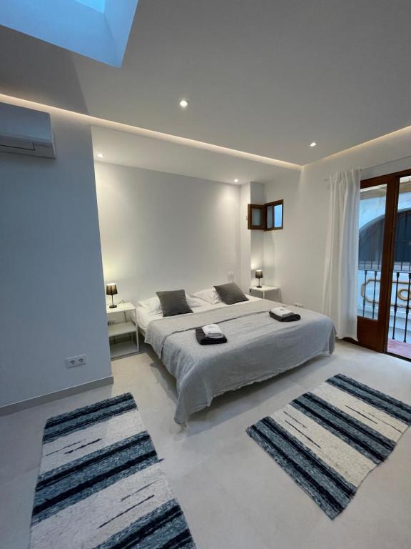 a white bedroom with a large bed and two rugs at Casa Florinda Tarifa in Tarifa