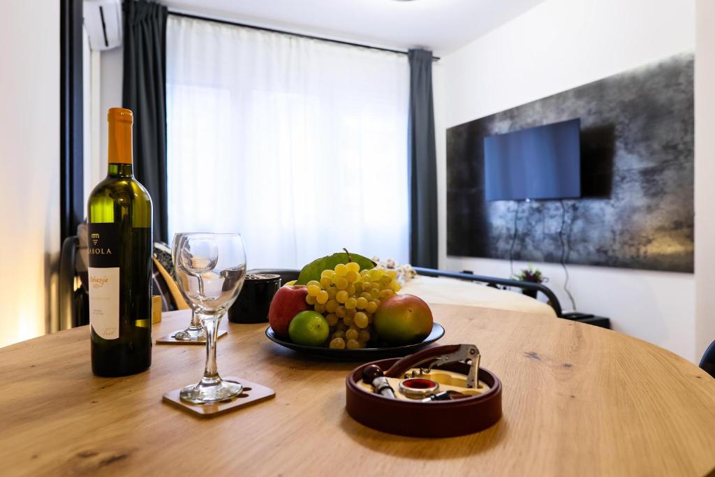 Una botella de vino y un bol de fruta sobre una mesa de madera. en Charm & Cozy studio Ravnice, en Zagreb