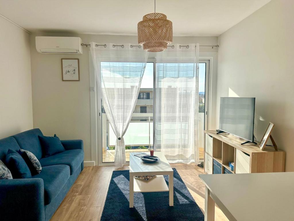 un salon avec un canapé bleu et une grande fenêtre dans l'établissement Appartement 2 pièces, à proximité de la plage, à Port-la-Nouvelle