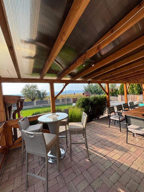 a patio with a table and chairs under a wooden roof at Parti Apartman in Balatonfůzfő