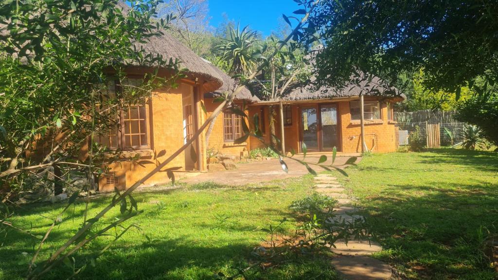 una pequeña casa amarilla con techo de hierba en A2B Eco Farm, Byrne Valley, KZN, en Byrne