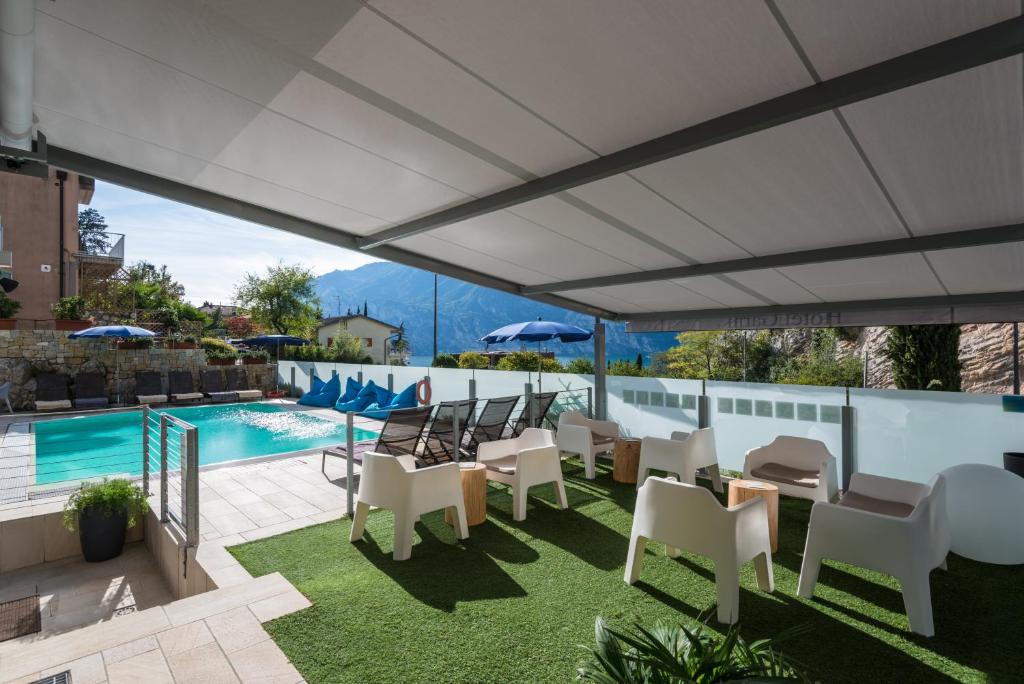 eine Terrasse mit Stühlen, einem Tisch und einem Pool in der Unterkunft SeeLE Garda Hotel in Nago-Torbole