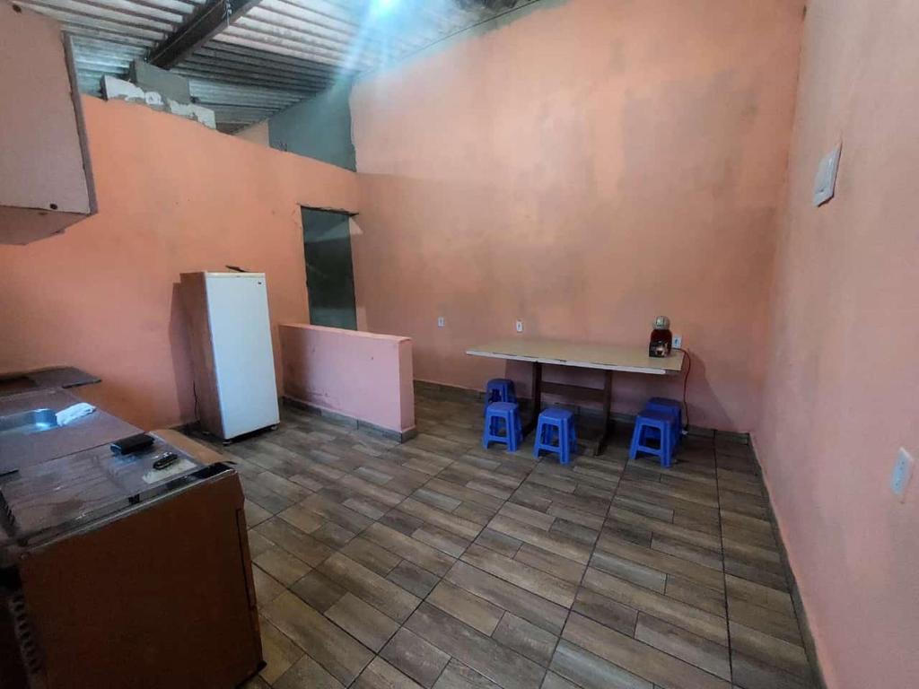 a kitchen with a table and two blue stools at Casa da rafaa in Itanhaém