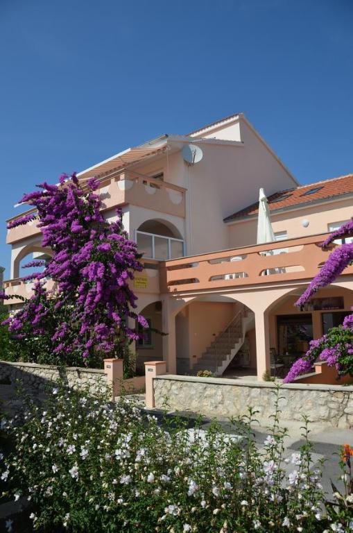 a building with purple flowers in front of it at Apartments Jadranka in Novalja