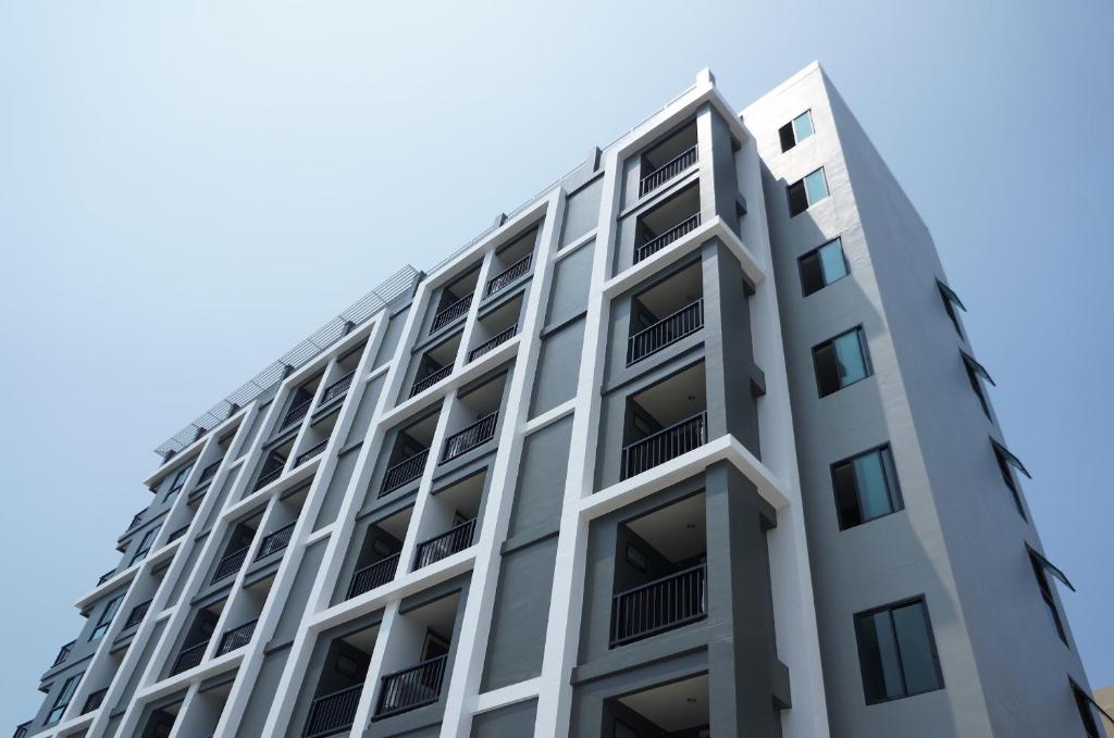 邦賢的住宿－三葉草公寓式酒店，一座高大的白色建筑,设有可望见蓝色天空的阳台