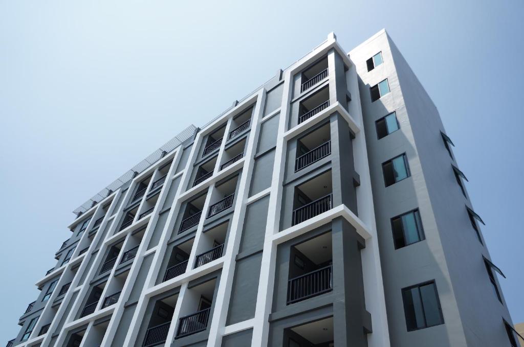 a tall white building with balconies against a blue sky at In Clover in Bangsaen