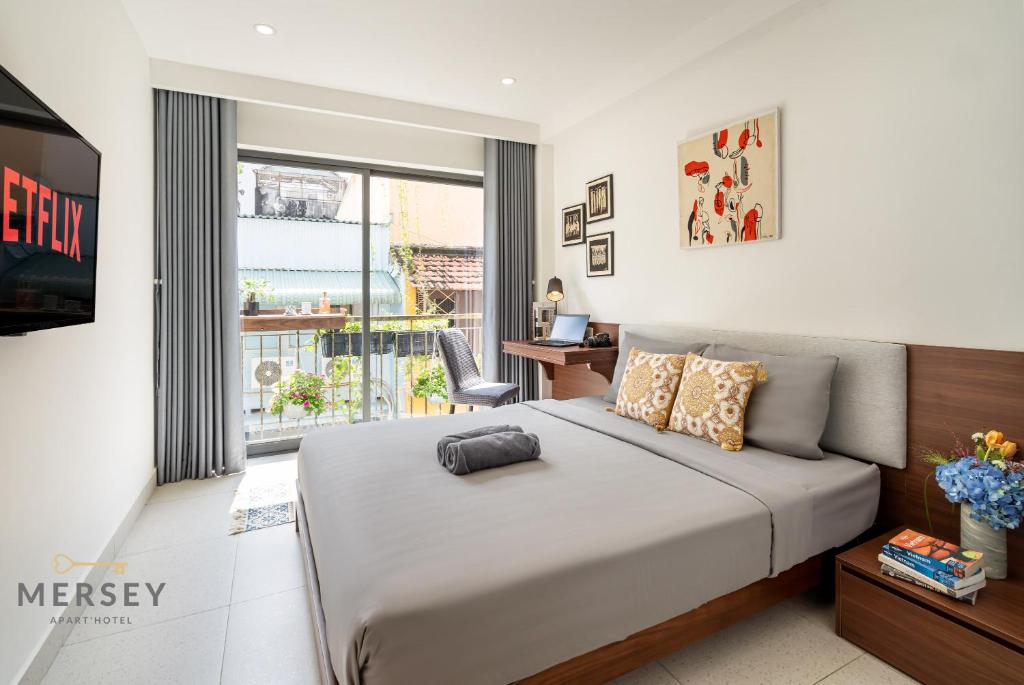 a bedroom with a bed and a desk and a window at Mersey Ben Thanh Saigon Apart'Hotel in Ho Chi Minh City