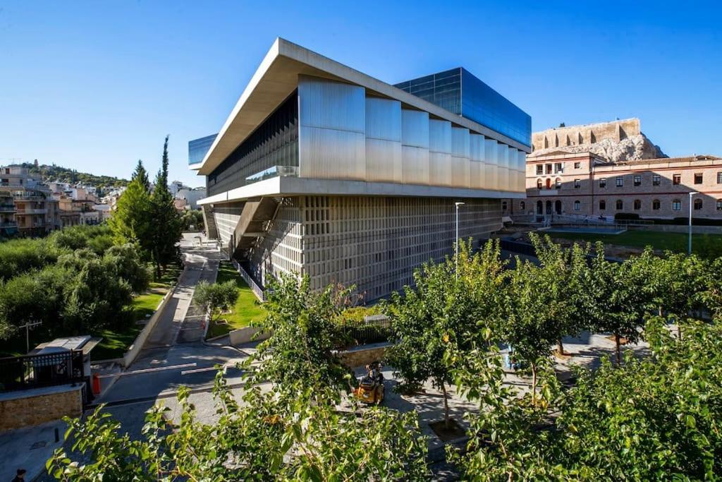 a building in a city with trees and buildings at Modern Apt opposite the Acropolis Museum in Athens