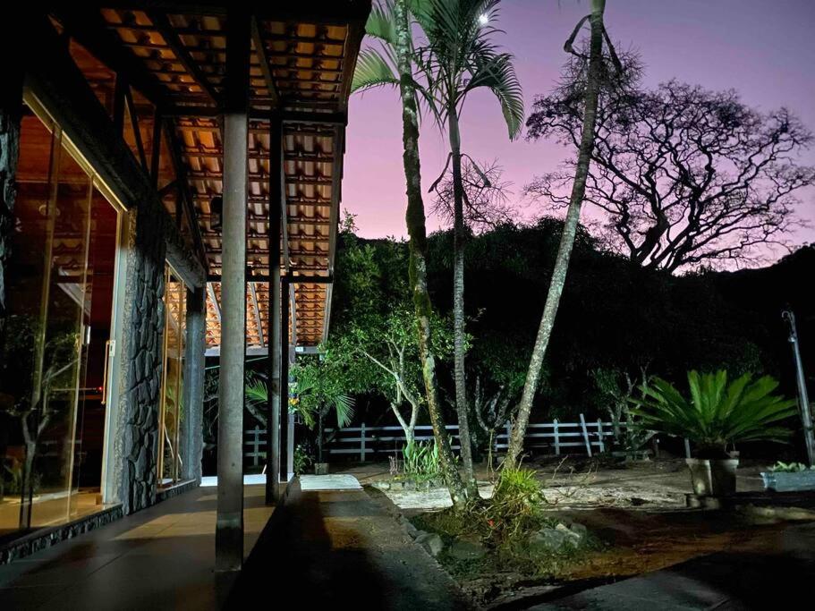 a porch of a building with palm trees and a fence at Chalé e Cachoeira Sítio Igrejinha Serra da Bocaina in Bananal