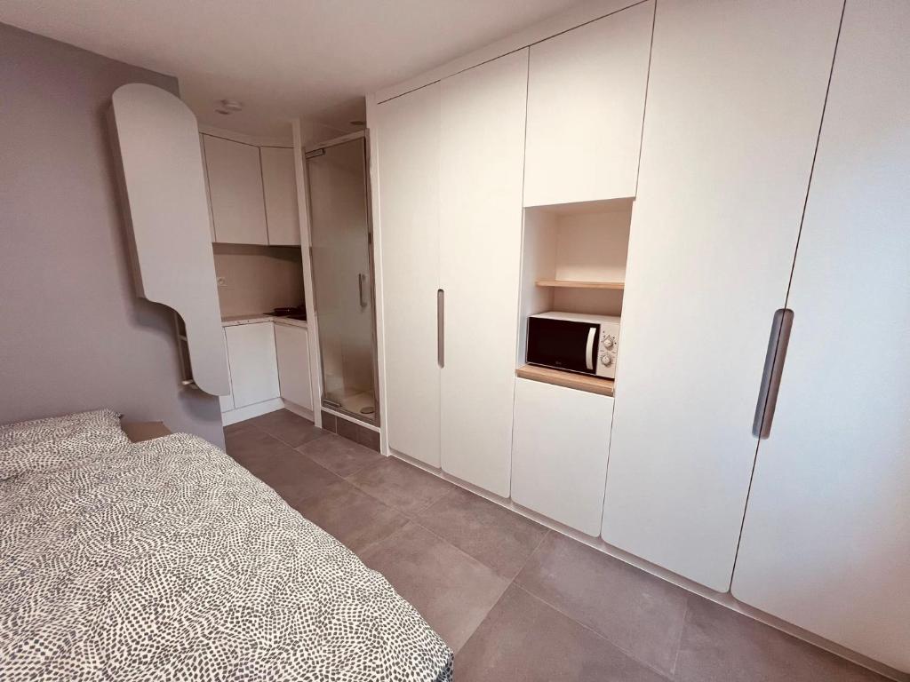 - une chambre avec un lit et une armoire blanche dans l'établissement Charming Studio near Châtelet Saint Sauveur, à Paris