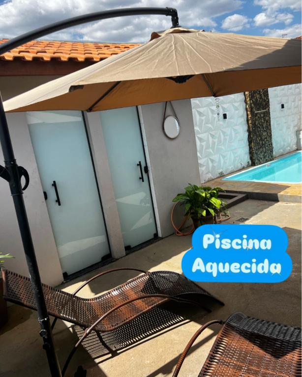 a patio with an umbrella next to a pool at Chacara Pinheiros piscina climatizada Próx a feira de malhas, Socorro SP in Socorro