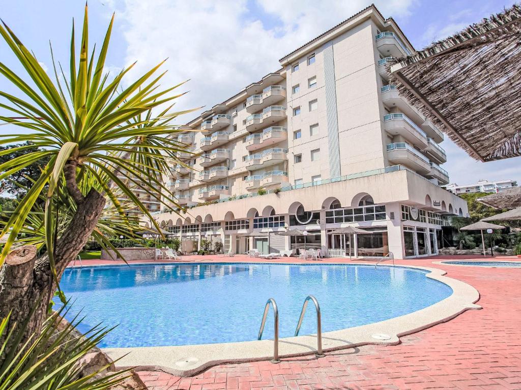 a swimming pool in front of a large building at Apartment Blanes Beach by Interhome in Blanes