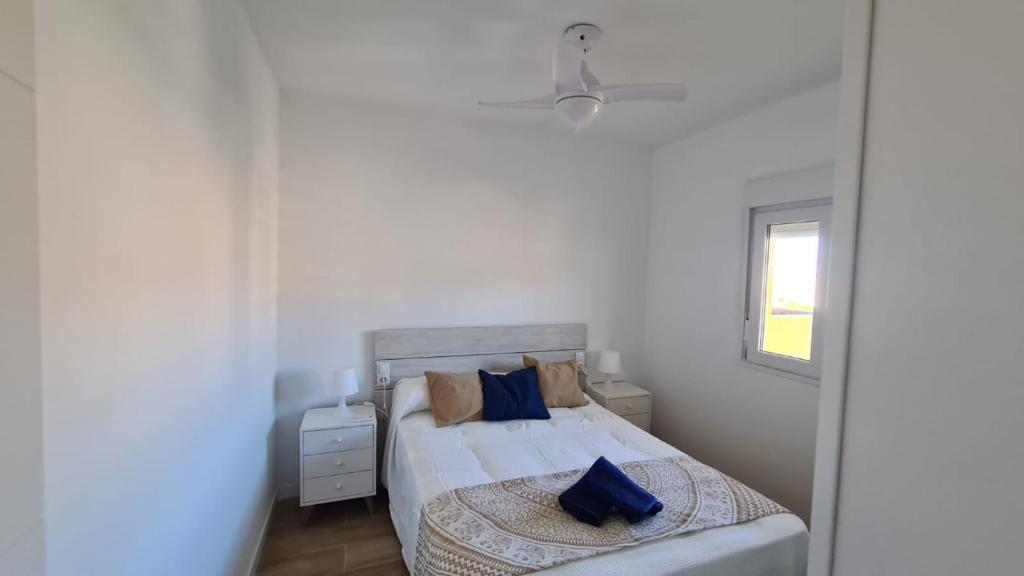 a bedroom with a bed with blue pillows and a window at CT 344 AL - Faro's Teckel Apartments Geminis Sky in Aguadulce