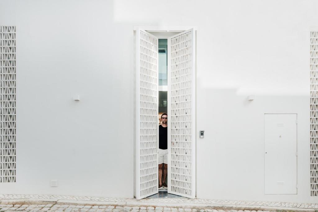 a woman standing in the doorway of a white building at Casa da Fé in Lagoa