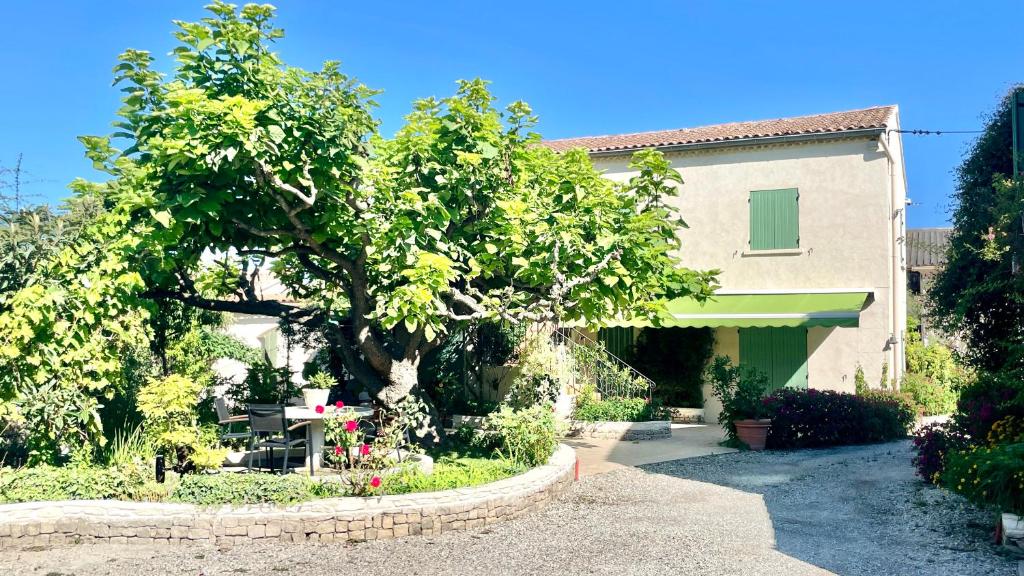 dom z drzewem i stołem przed nim w obiekcie Rendez-vous au soleil de Provence - gite 4 personnes 80m2 - coin jardin - climatisation w mieście Cheval-Blanc
