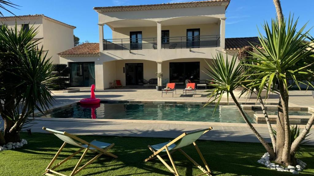 a house with a swimming pool and two lawn chairs at Villa Emeraude-Joyaux de Provence in Saint-Étienne-du-Grès