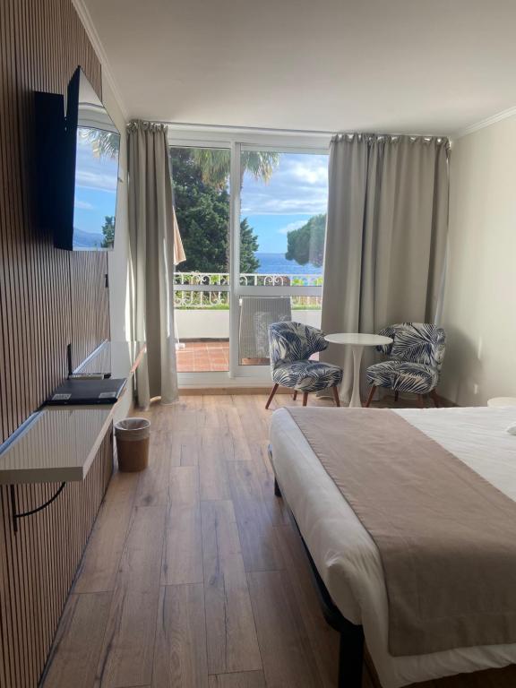 a hotel room with a bed and a large window at Les Alcyons in Le Lavandou