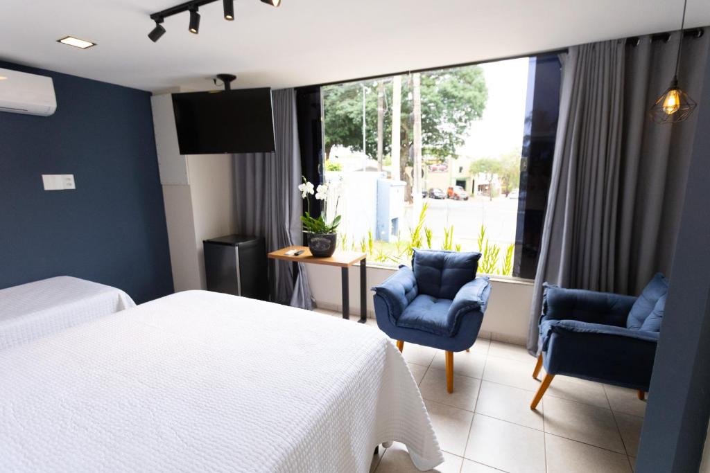 a bedroom with a bed and two chairs and a window at Pousada Premiatto in Holambra