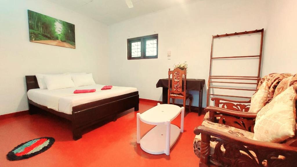 a bedroom with a bed and a chair in it at Sohansa Guesthouse in Weligama
