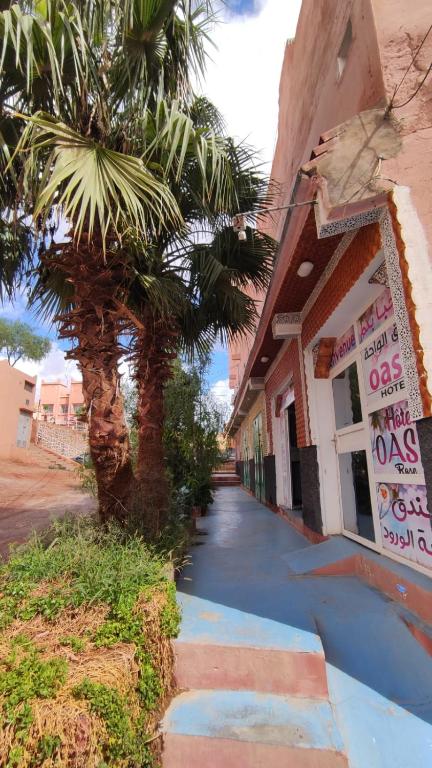 a building with a palm tree next to a street at Hotel Oasis Tinghir in Tinerhir