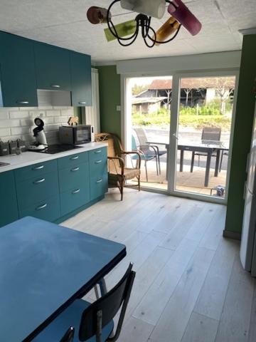une cuisine avec des armoires bleues et une table et un patio dans l'établissement Au calme, à Villersérine