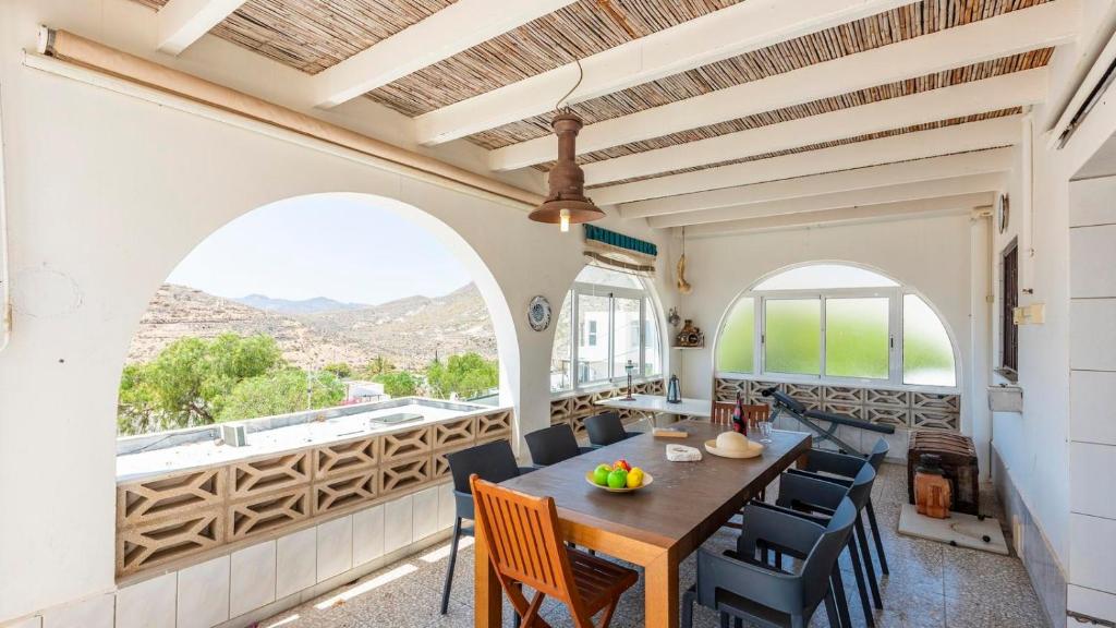 a dining room with a table and chairs and windows at Chalet El Nido Níjar by Ruralidays in Níjar