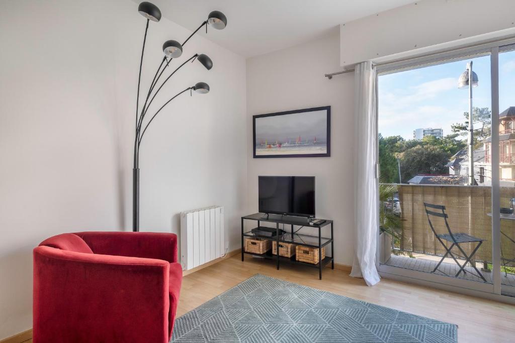 un salon avec une chaise rouge et une télévision dans l'établissement Appartement avec double terrasse - 170m de la plage, à La Baule