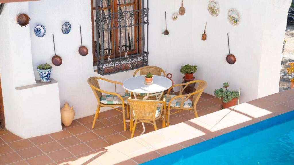 a patio with a table and chairs next to a pool at Huerta La Niña Arenas Órgiva by Ruralidays in Órgiva
