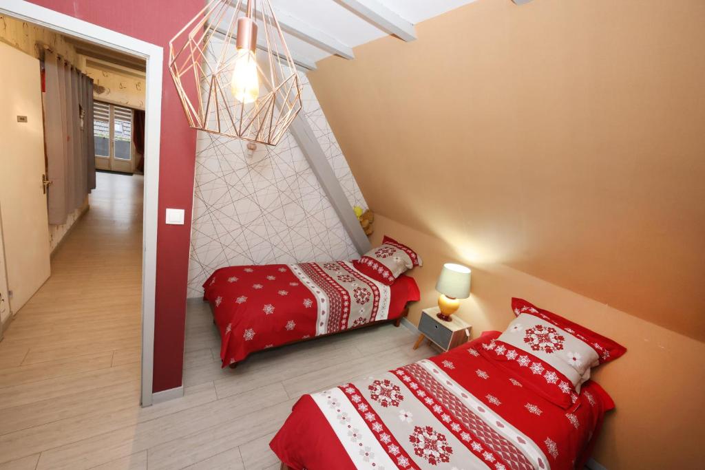2 Betten in einem Zimmer mit roter Bettwäsche in der Unterkunft Le clocher aux cigognes au village de Bergheim in Bergheim