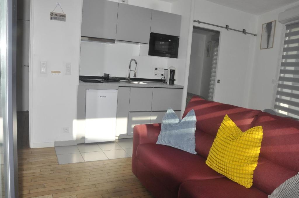 - un salon avec un canapé rouge et des oreillers jaunes dans l'établissement Pépite Haut De Gamme tous conforts, à Romainville