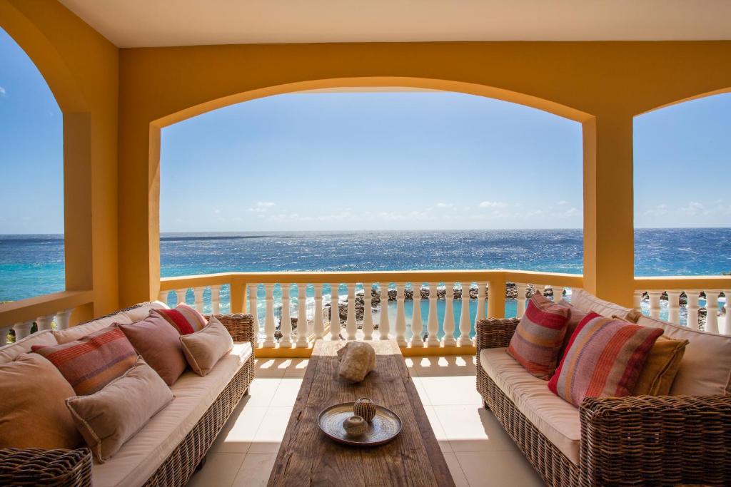a living room with a couch on a balcony with the ocean at The Strand - The Beach, Penthouse 4A in Willemstad