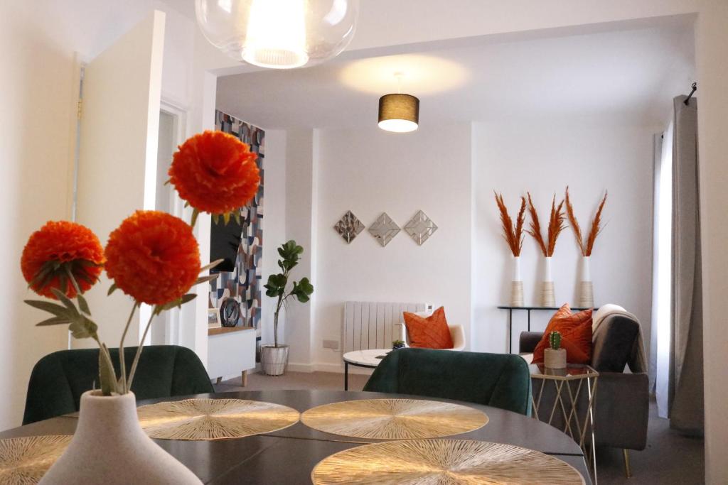 a living room with a table and some orange flowers at Top Spot 2-Bed Spacious Apartment Town Centre Train Station WIFI in Colchester