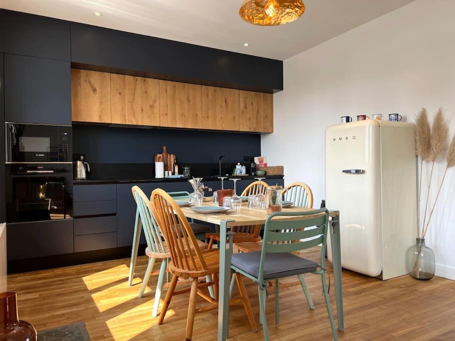 une cuisine avec une table, des chaises et un réfrigérateur dans l'établissement Le California ! 250m des plages, à Larmor-Plage