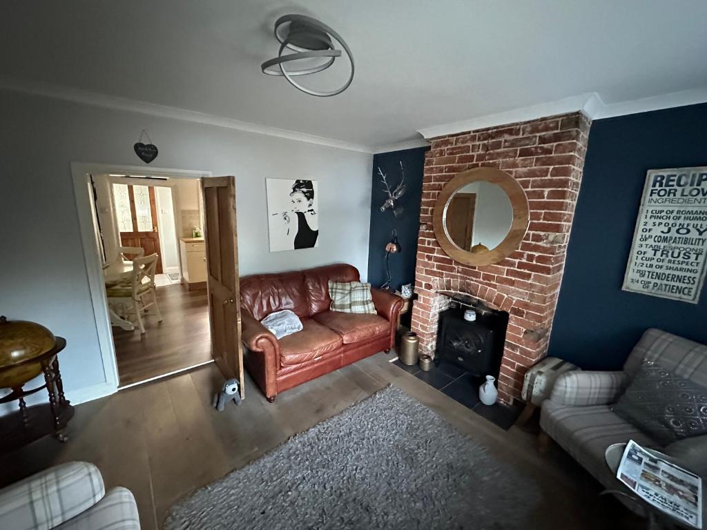 a living room with a couch and a brick fireplace at April Cottage Ringwood in Ringwood